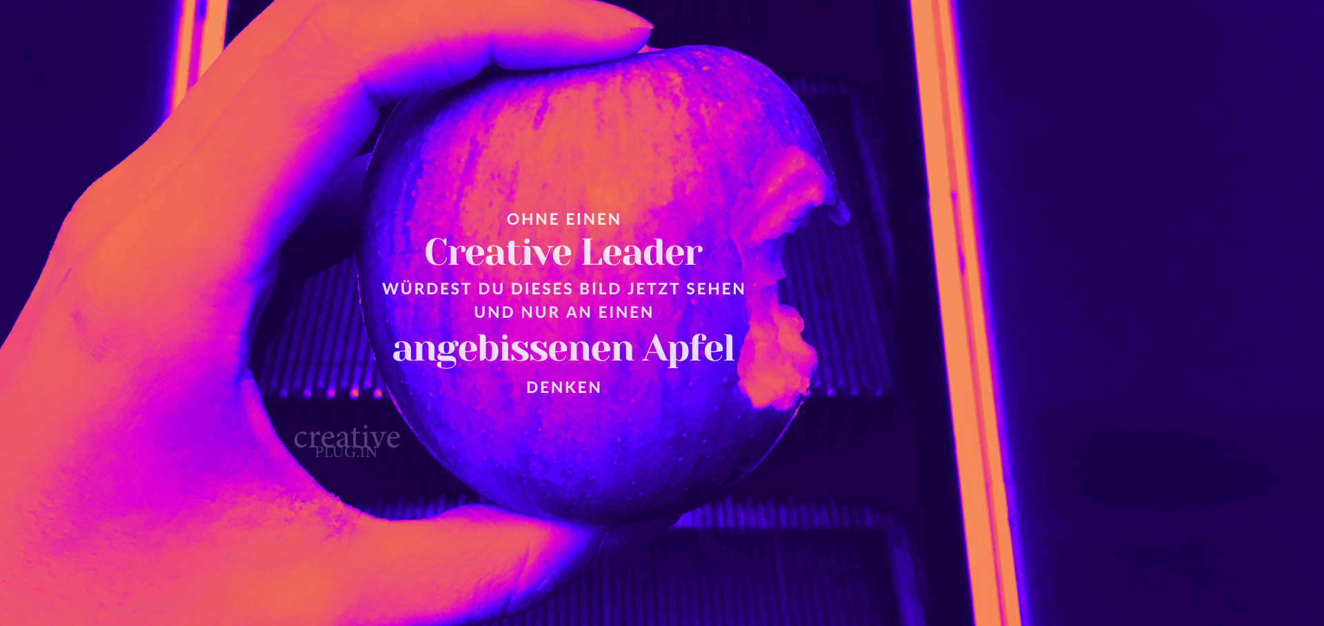 Eine Hand hält einen roten Apfel mit einem digitalen Text auf einem Bildschirm im Hintergrund.